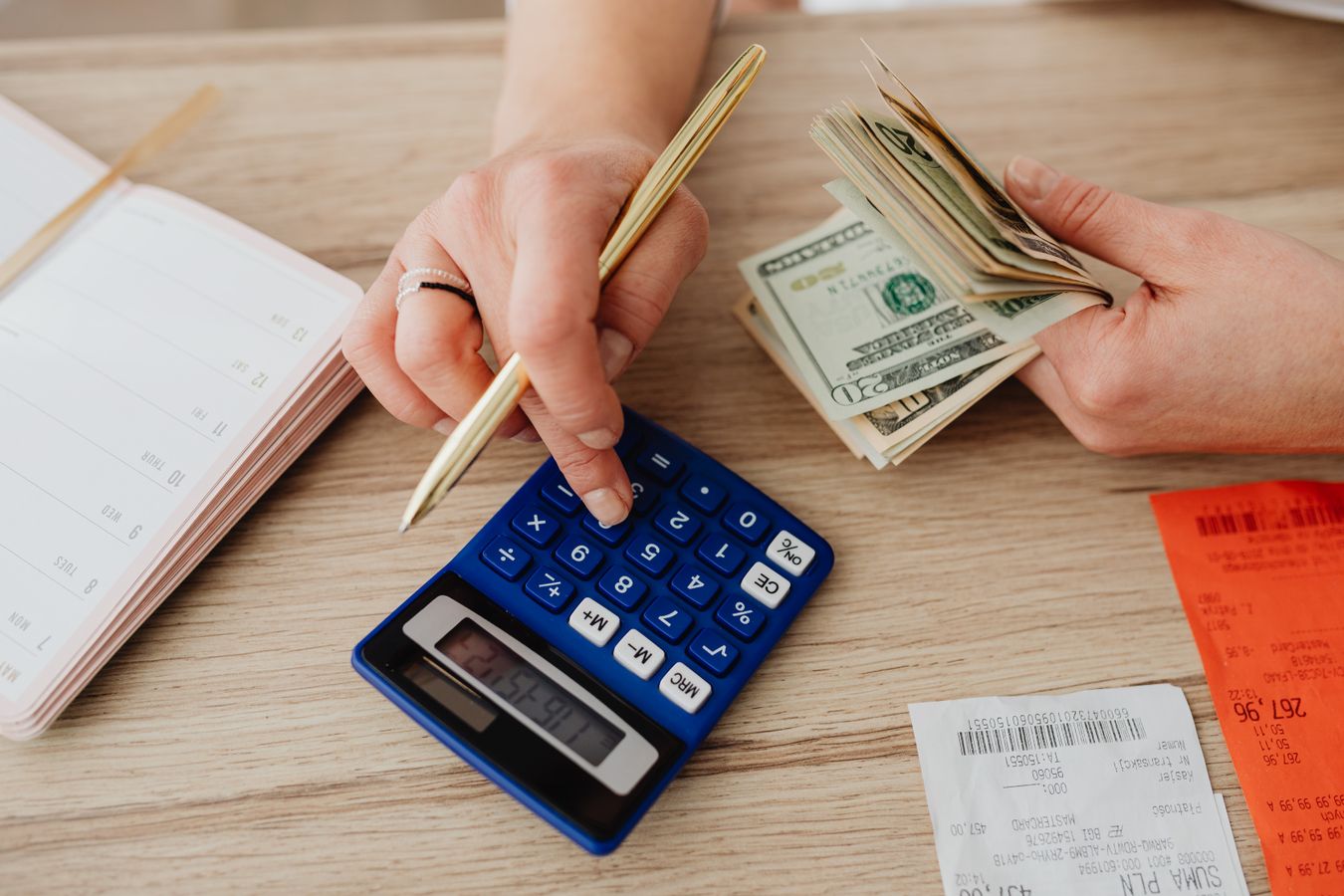 Hands using a calculator with cash and receipts, illustrating the limits of a kitchen renovation cost calculator