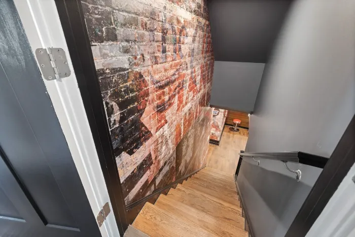 Staircase down to a basement beside an exposed brick wall
