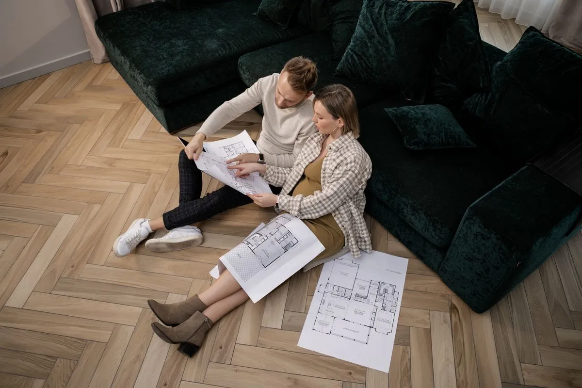 Couple sitting on a floor reviewing renovation plans