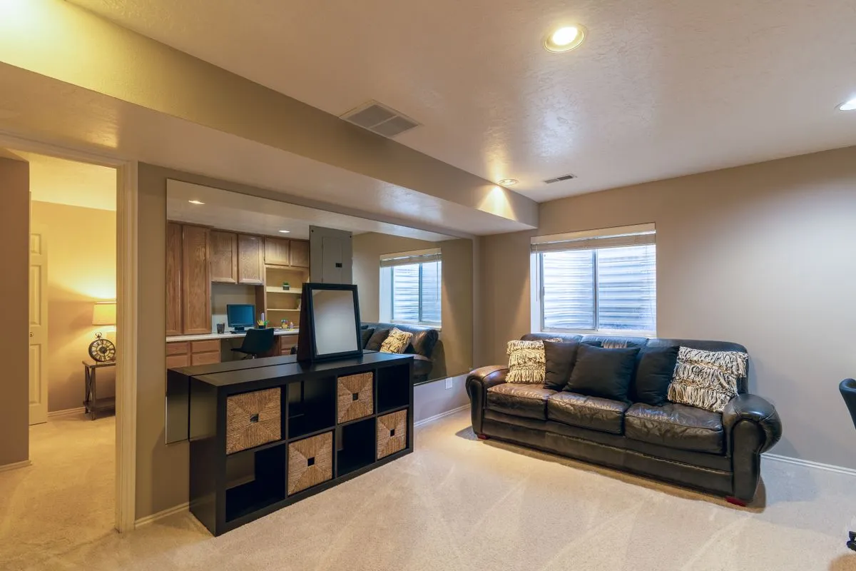 Finished basement sitting room with a leather sofa and bright windows