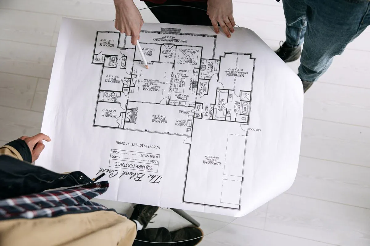 Two people reviewing a house floor plan on a table